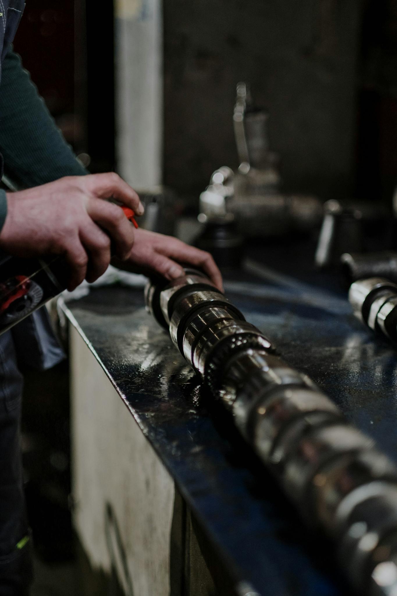 Detailed close-up of hands spraying a metal part in an industrial setting.